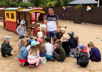 Mężczyzna z alpakami w otoczeniu dzieci
