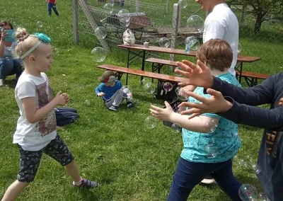 Dzieci bawiące się na trawie wśród baniek mydlanych